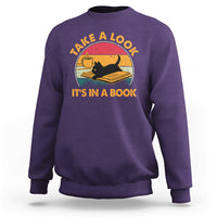 Purple sweatshirt with cat reading book graphic and circular text print.