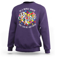 Purple crewneck sweatshirt with colorful Be Kind graphic and puzzle heart text