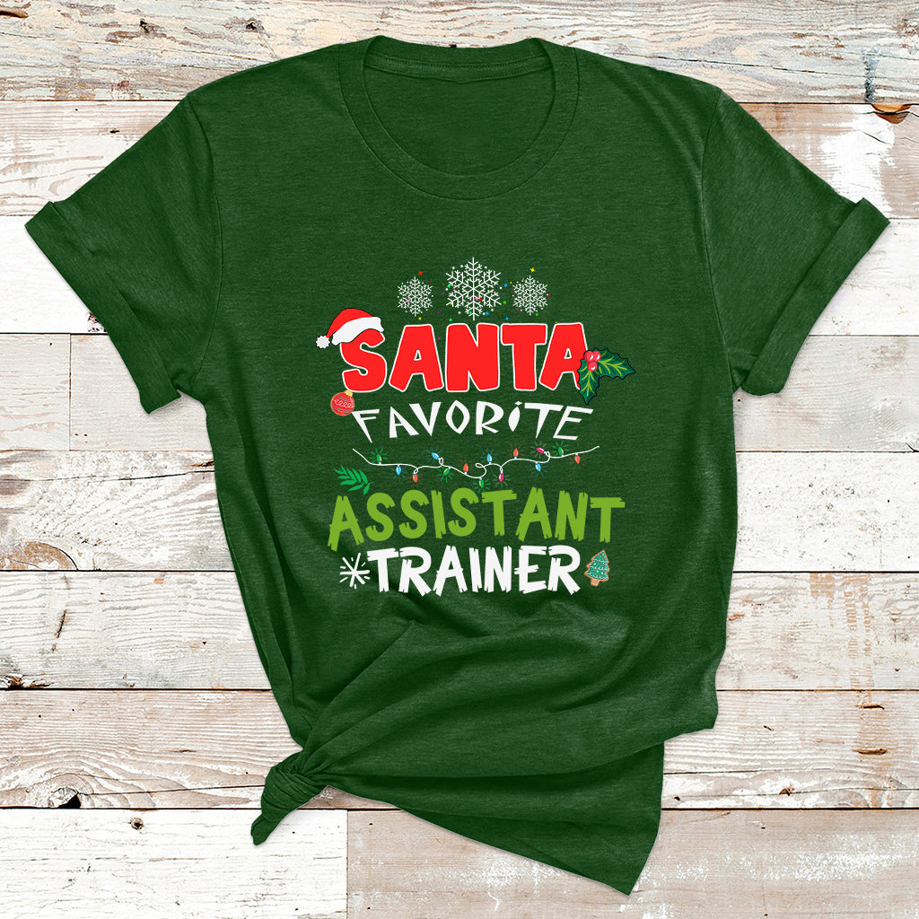 Santa-themed T-shirt in green with “SANTA FAVORITE ASSISTANT TRAINER” holiday graphic.