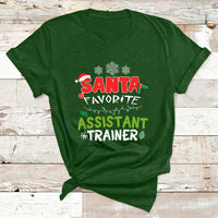 Santa-themed T-shirt in green with “SANTA FAVORITE ASSISTANT TRAINER” holiday graphic.