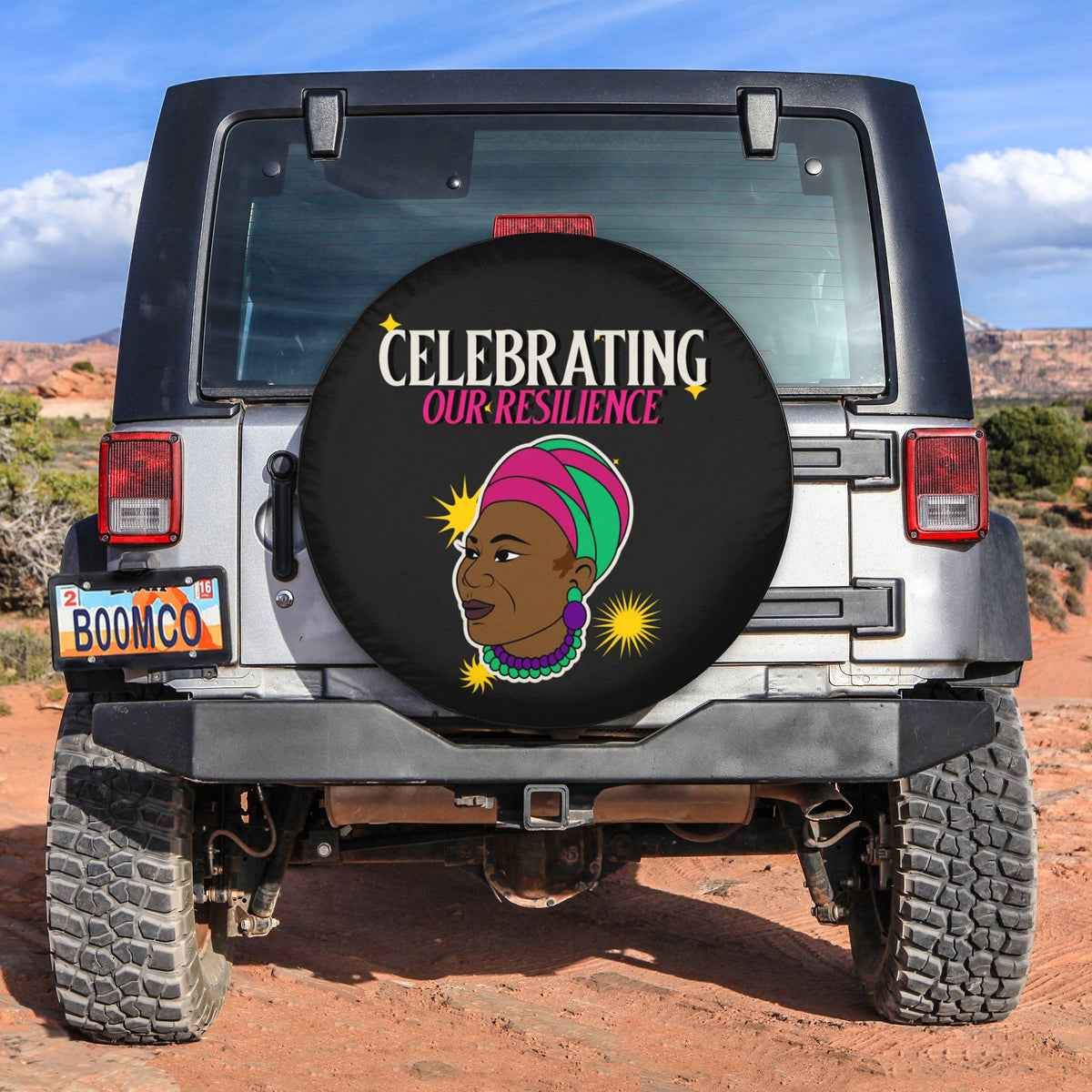 Spare tire cover, black, “Celebrating Our Resilience” graphic with face illustration