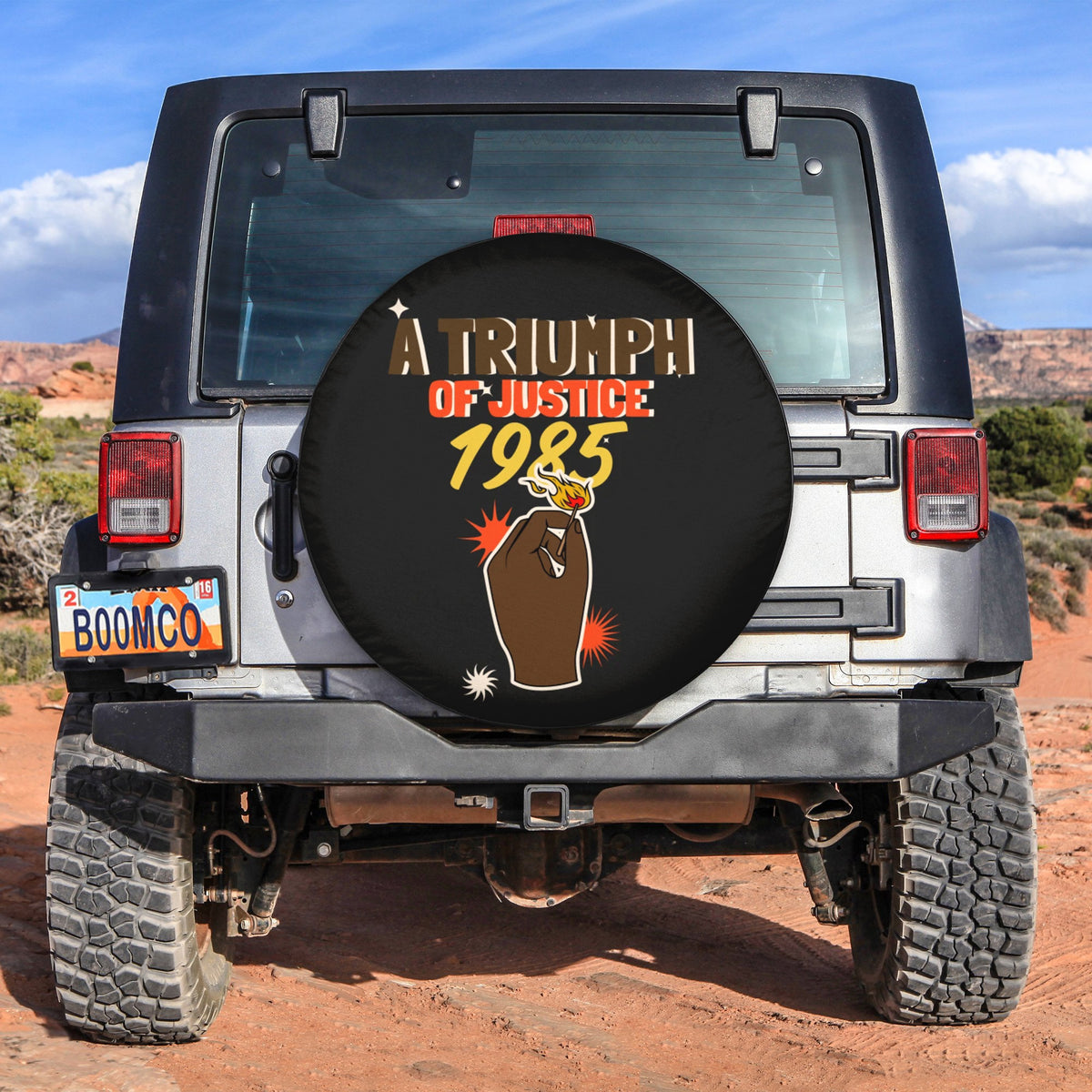 Black spare tire cover with circular Triumph of Justice 1985 graphic and gold text
