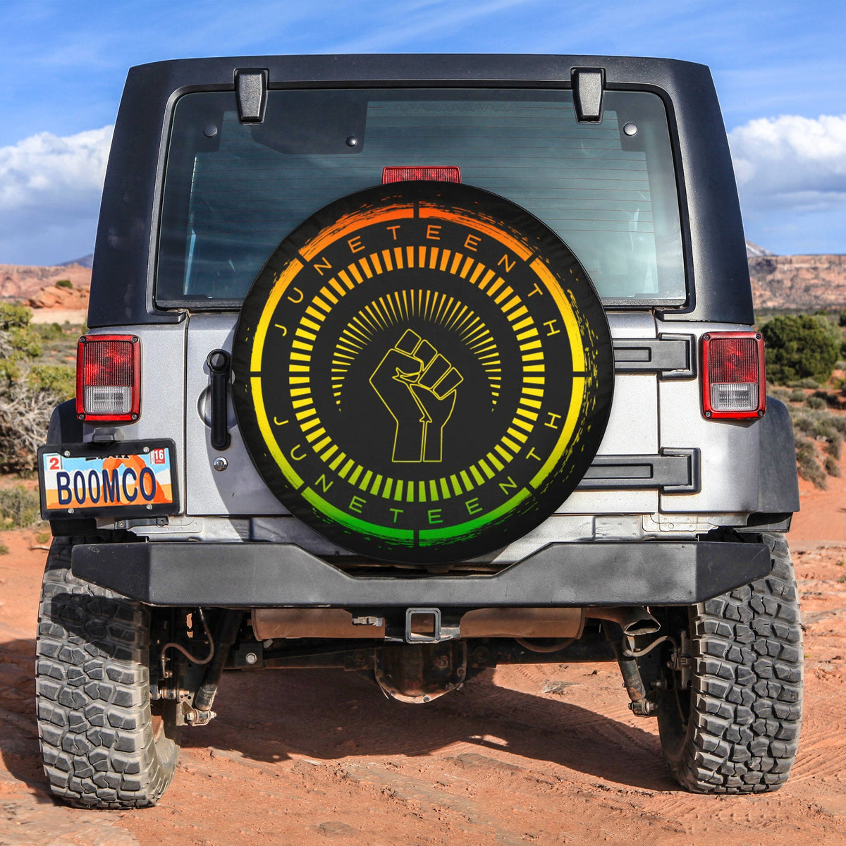 Round spare tire cover with black background, colorful ring, and raised fist graphic