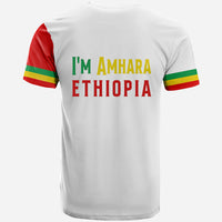 White T-shirt with 'I'm Amhara Ethiopia' graphic and tricolor stripe sleeves.