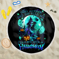 Round black Halloween beach blanket with blue witch skull graphic and white fringe, laid flat