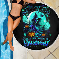 Black Halloween beach blanket with blue witch skull graphic and white fringe edge, poolside