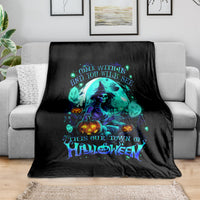 Black Halloween blanket with neon teal skull-and-witch graphic, draped on couch