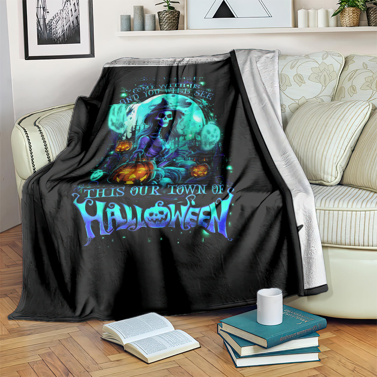 Black Halloween blanket with glowing teal witch skull print, folded on sofa arm