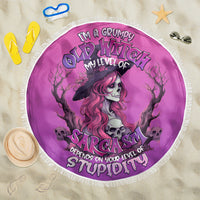 Pink round beach blanket with fringe, witch skull portrait, bold “Sarcasm” text