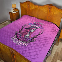 Pink quilt with diamond quilting and witch-skull print on top of a bed
