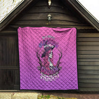 Pink quilt with diamond stitching and witch-skull graphic displayed on a porch
