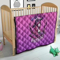 Pink quilt blanket with diamond quilting and witch-skull print on a baby bed