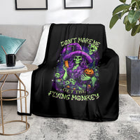Black blanket with neon witch skull and 'FLYING MONKEY' text over sofa