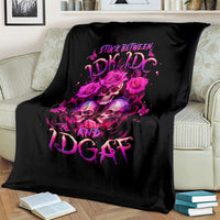 Black skull graphic throw blanket with pink roses and lettering, spread on sofa.