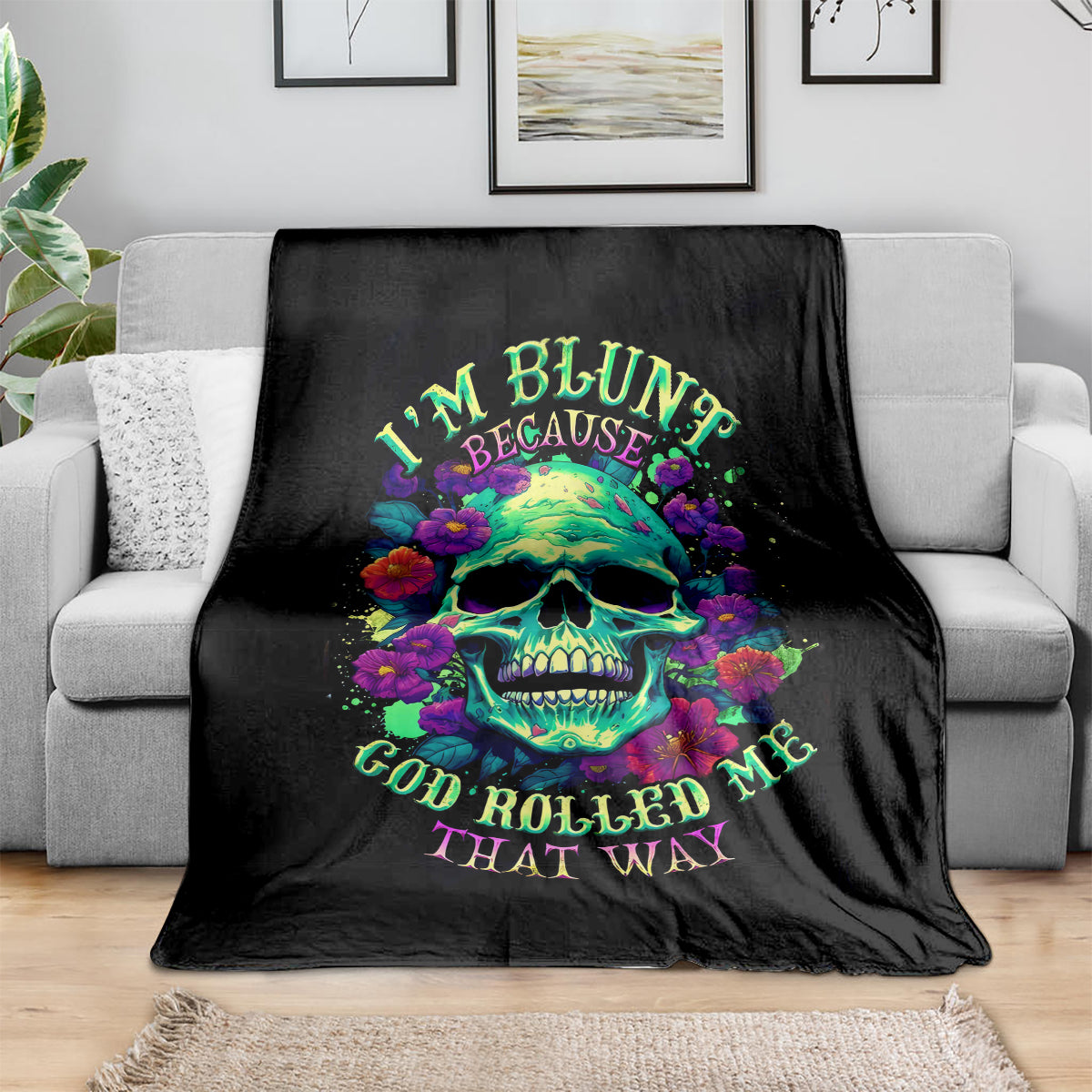 Black skull and flower print blanket on a gray sofa, neatly draped across cushions.