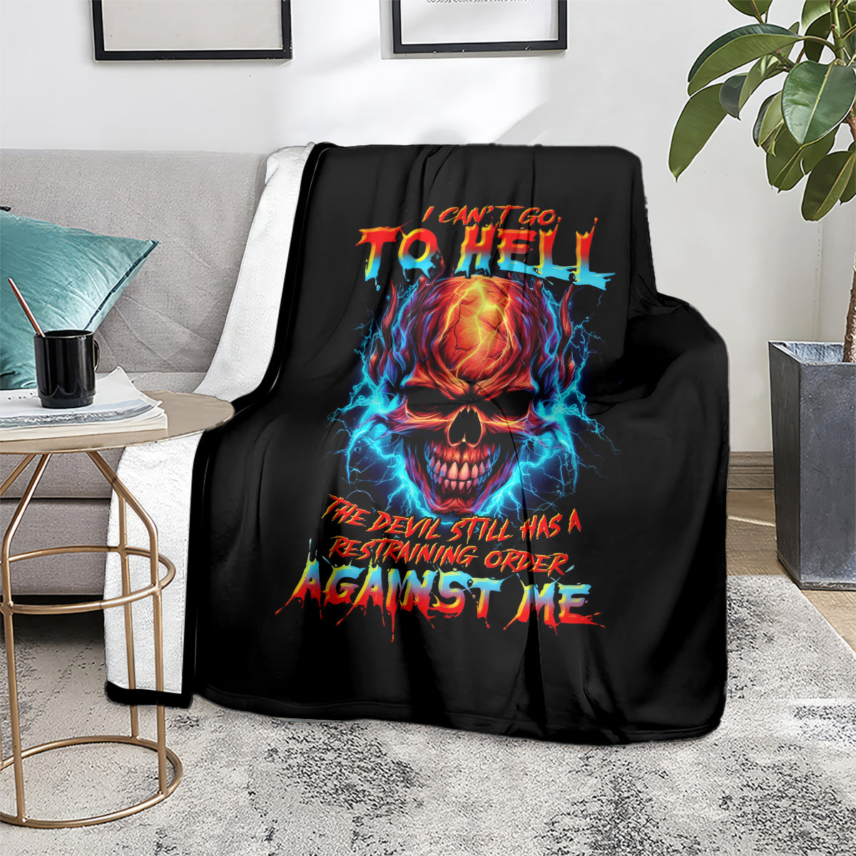 Black skull devil graphic blanket with bright flame skull and bold text, on sofa