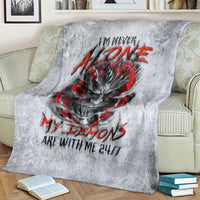 Grey blanket with devil skull artwork and red accents, laid across a bed