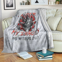 Grey devil skull blanket with red lettering, draped on couch with books nearby