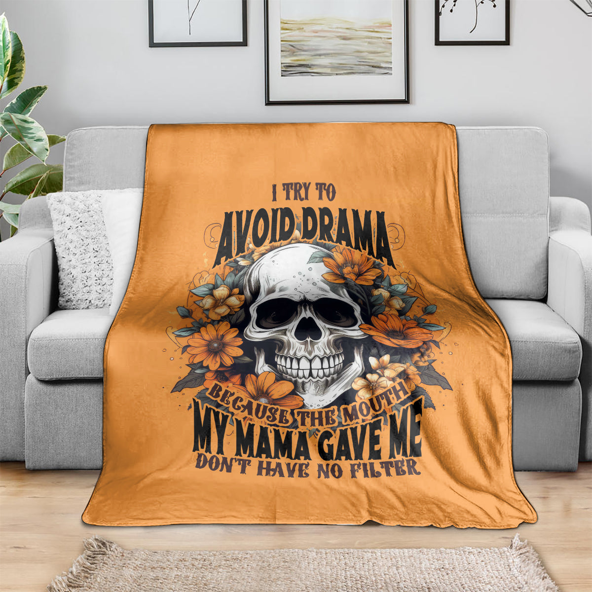 Orange throw blanket with smiling skull and orange floral graphic, on sofa