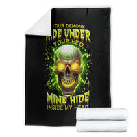 Folded black blanket with neon green skull design and “Your Demons Hide Under Your Bed”