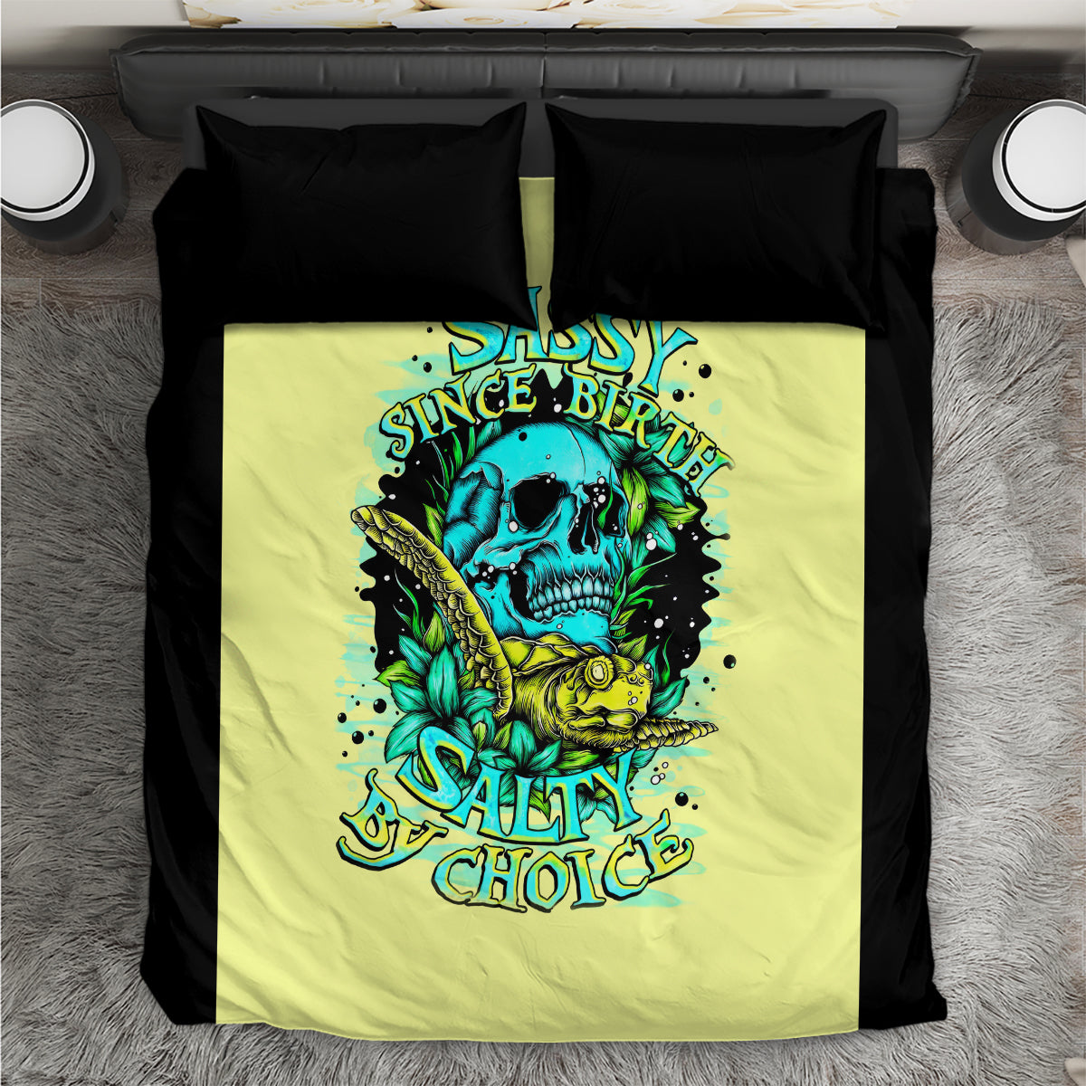 Yellow duvet cover with skull and turtle graphic, flanked by two black pillowcases