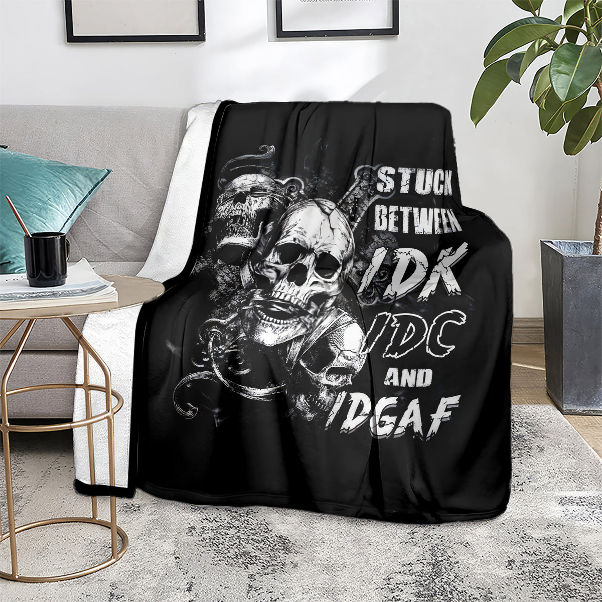 Black skull graphic throw blanket with white lettering, spread on a gray sofa