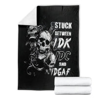 Black skull graphic throw blanket with white text design, folded with white towels