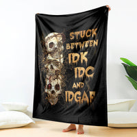 Black skull graphic throw blanket draped over a backrest, gold lettering and skulls