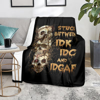 Black skull graphic throw blanket on a gray sofa, gold skull artwork and lettering
