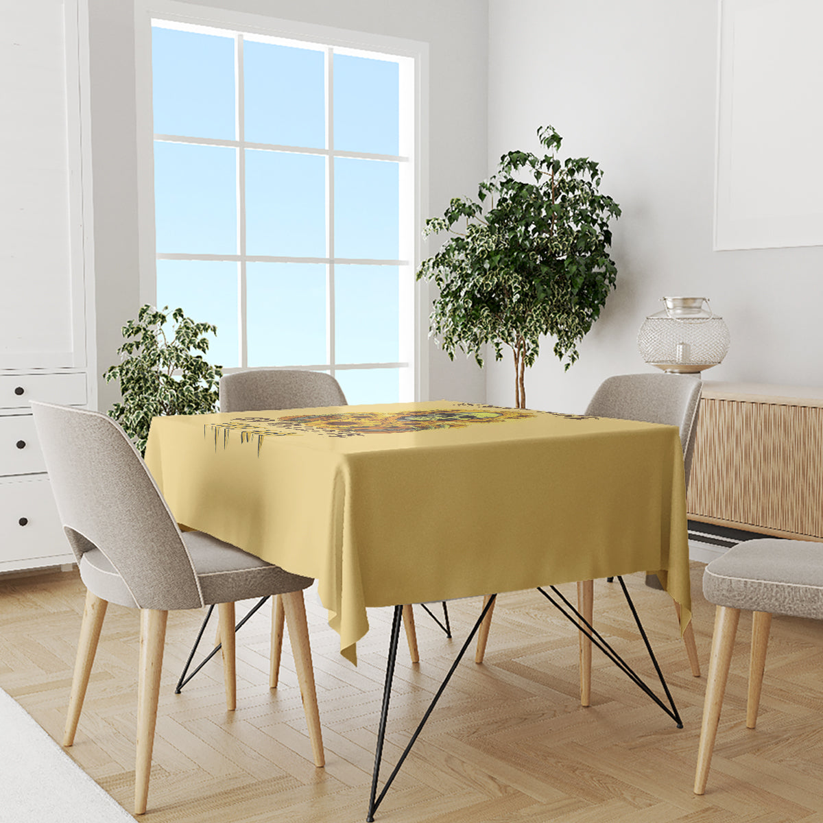 Yellow tablecloth draped on dining table with skull-and-sunflower drip artwork.