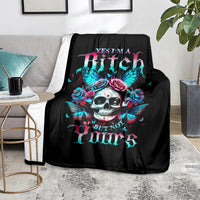 Black skull blanket with butterfly wings and pink roses graphic, on a gray couch