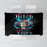 Black tablecloth featuring a skull, roses, butterflies, and bright multicolor lettering.