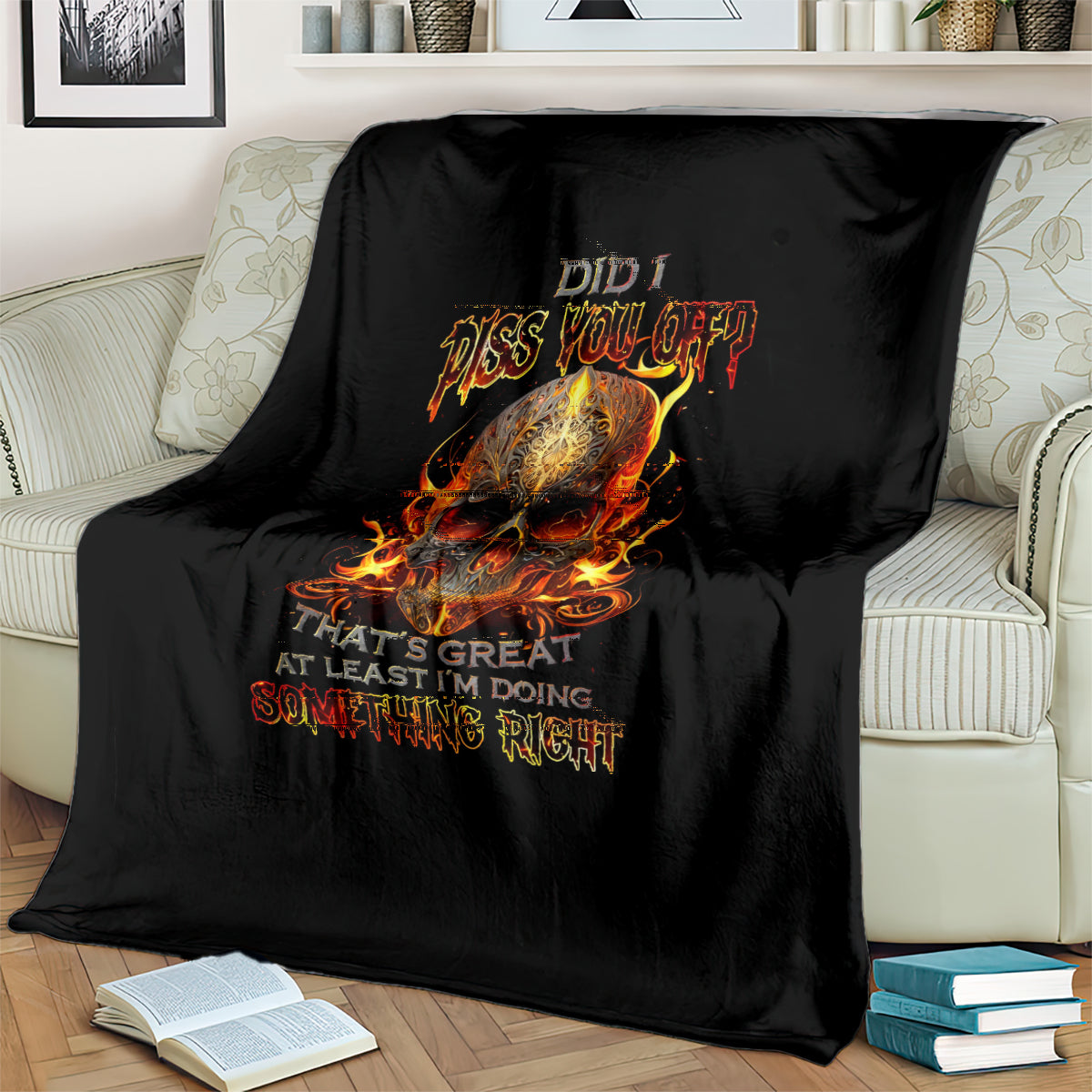 Black throw blanket with flaming skull artwork, draped over couch seat
