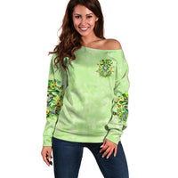 Green off-shoulder sweater with small skull and floral emblem on chest