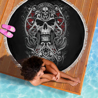 Black round beach blanket with skull artwork and red heart flourishes, white fringed border