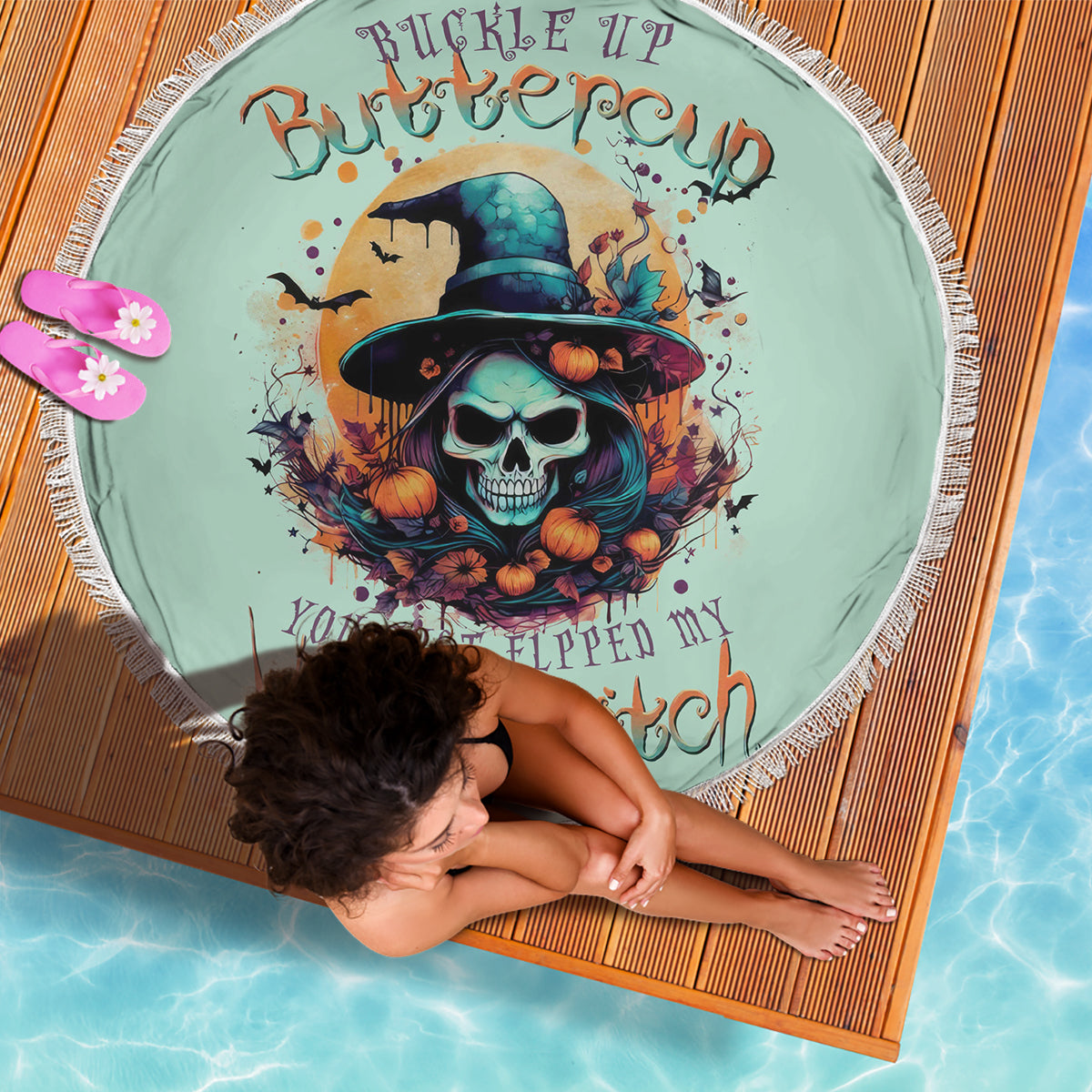 Round teal beach blanket with fringe edge, witch skull and pumpkins graphic