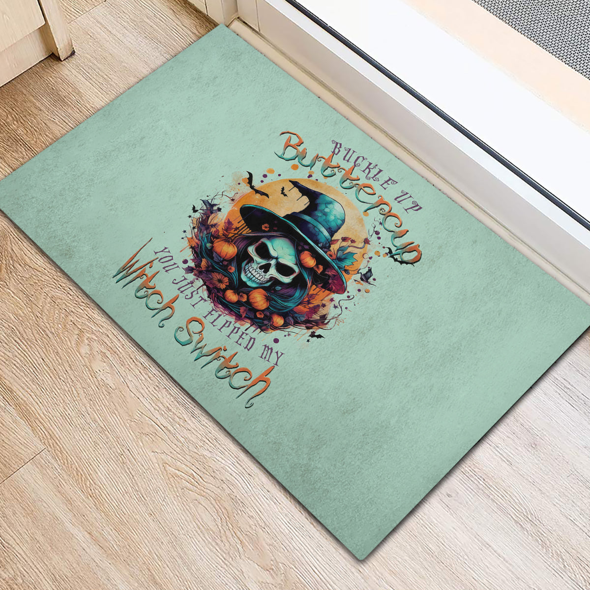 Teal rubber doormat with witch skull graphic and 'Buckle Up Buttercup' text