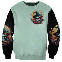 Unisex mint green sweatshirt with small skull witch hat print and black sleeves