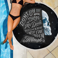 Black round beach blanket close-up with skull text print and fringed white edge