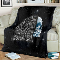 Black skull quote fleece blanket on sofa, starry print with circular typography