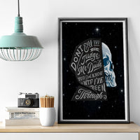 Framed black canvas wall art with blue skull portrait and curved quote text on star field