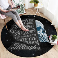Round black graphic area rug with skull portrait and quote text, star-speckled pattern