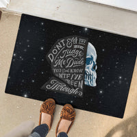 Black rubber doormat with sad skull print, starry background, and bold slogan wording