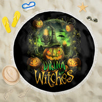Round black beach blanket featuring green cauldron and pumpkins, “Drink Up Witches” text