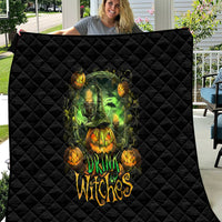 Black quilted Halloween quilt with green witch skull and orange pumpkins, angled view