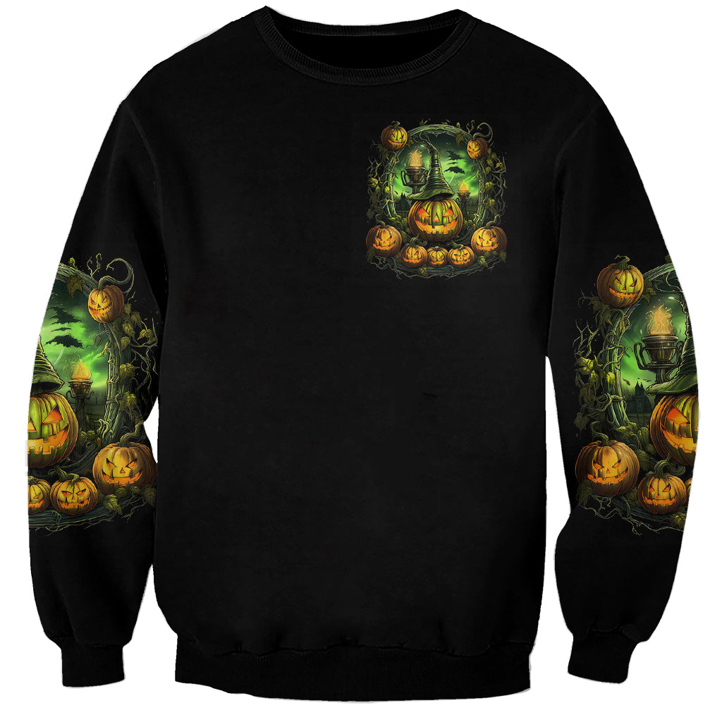 Black unisex sweatshirt with small green witch and pumpkins graphic on chest