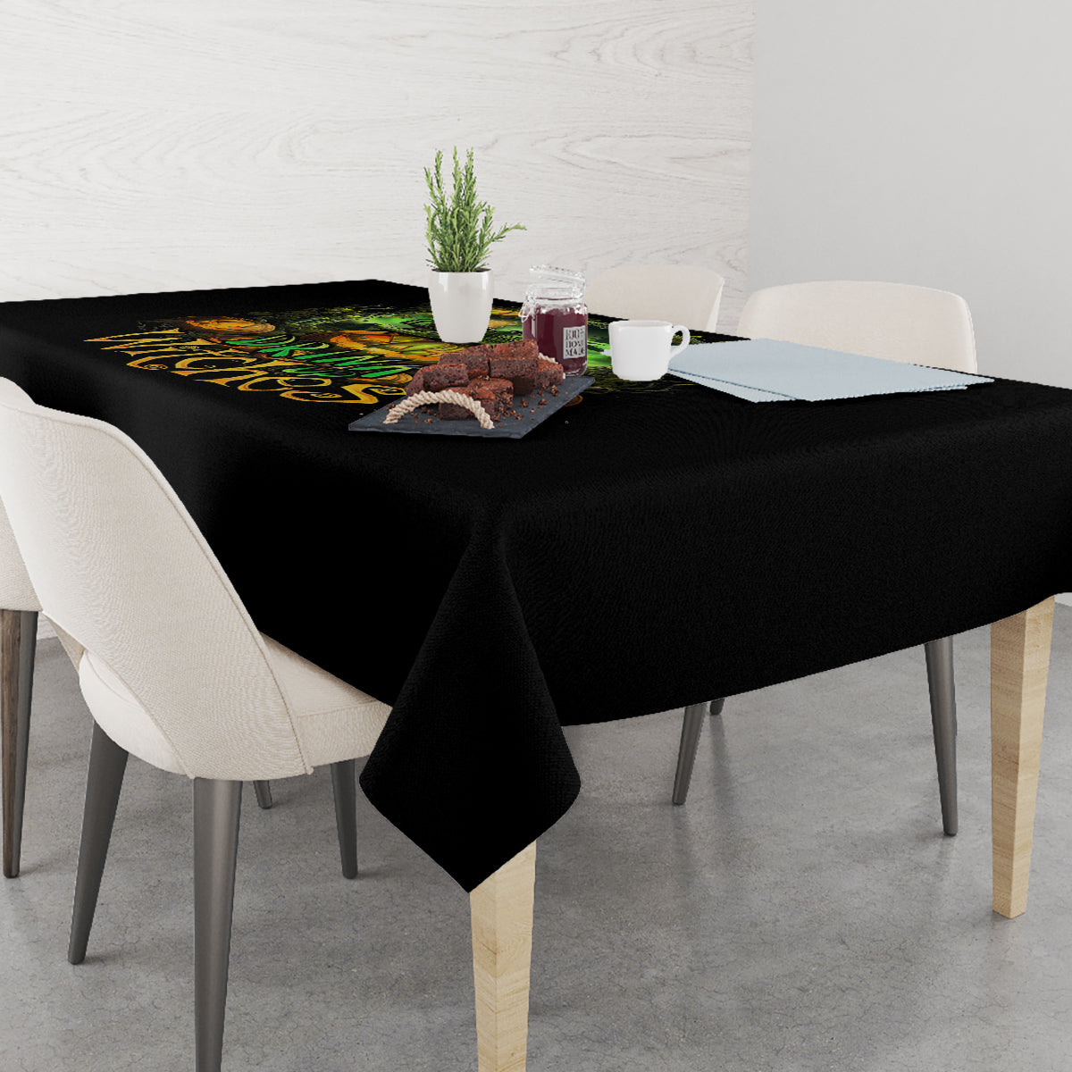 Black Halloween tablecloth draped over dining table with 'Drink up Witches' print.
