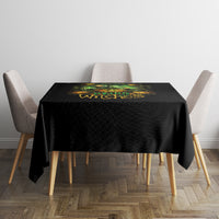 Black Halloween tablecloth on square table with green 'Drink up Witches' text graphic.