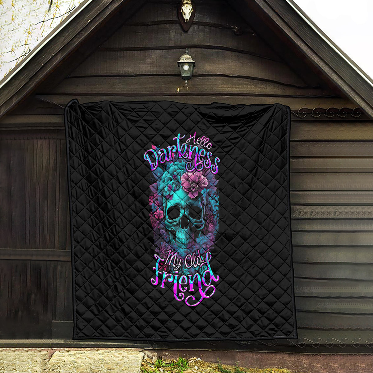 Black quilt with diamond stitching and colorful skull-flower design, hanging