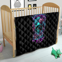 Black quilt with diamond stitching and teal skull-flower artwork, on crib